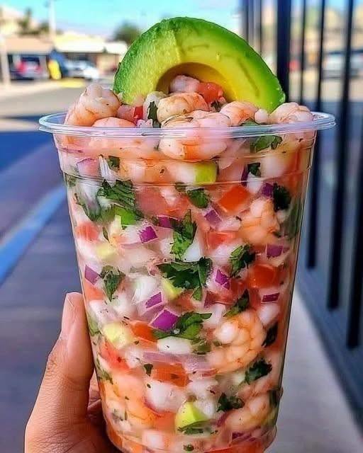 Mexican Shrimp Cocktail: 1 Easy Recipe For The Perfect Refreshing Appetizer 1 A top-down photo of a serving of chilled Mexican Shrimp Cocktail with tender shrimp, avocado chunks, and cucumber in a tall glass.