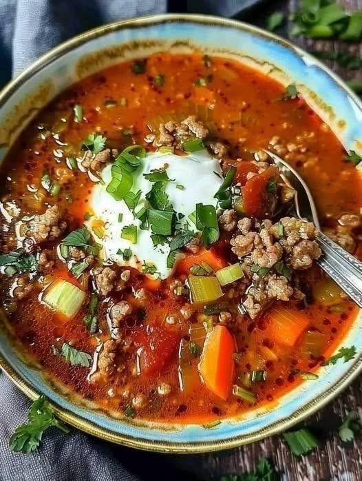 A hot bowl of Cheesy Taco Soup topped with shredded cheddar, tortilla chips, and fresh cilantro