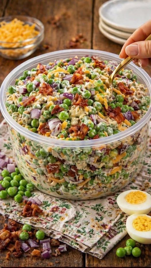 Delicious creamy bacon pea salad with sharp cheddar cheese and red onions in a white serving bowl